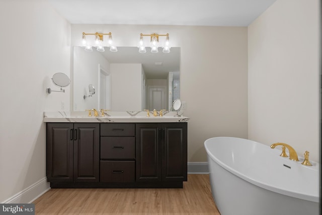 bathroom featuring double vanity, a soaking tub, baseboards, and wood finished floors