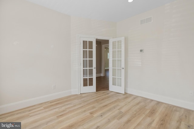 empty room with light wood-style floors, french doors, visible vents, and baseboards