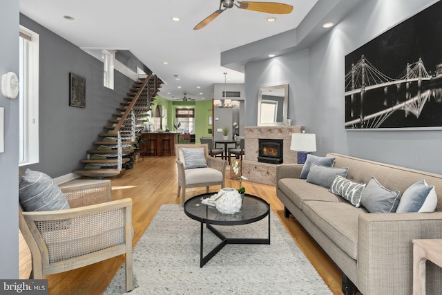 living room with a high end fireplace, recessed lighting, light wood finished floors, and stairs