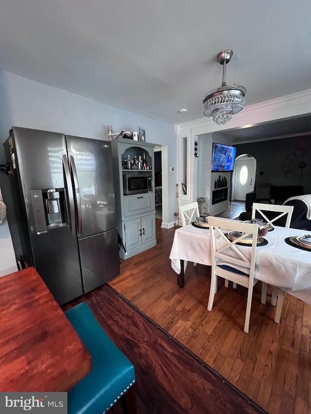 kitchen with stainless steel microwave, pendant lighting, hardwood / wood-style floors, and fridge with ice dispenser