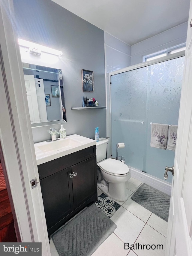 bathroom featuring tile patterned floors, vanity, a shower with door, and toilet