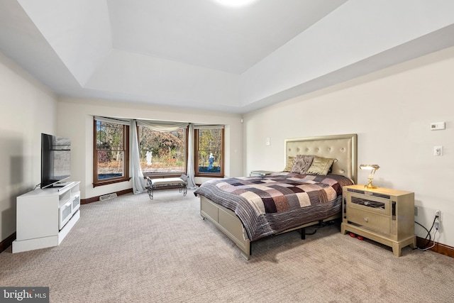 bedroom with light carpet and a tray ceiling