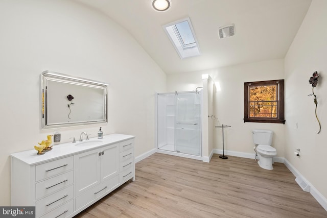 bathroom with vaulted ceiling with skylight, vanity, toilet, and hardwood / wood-style floors