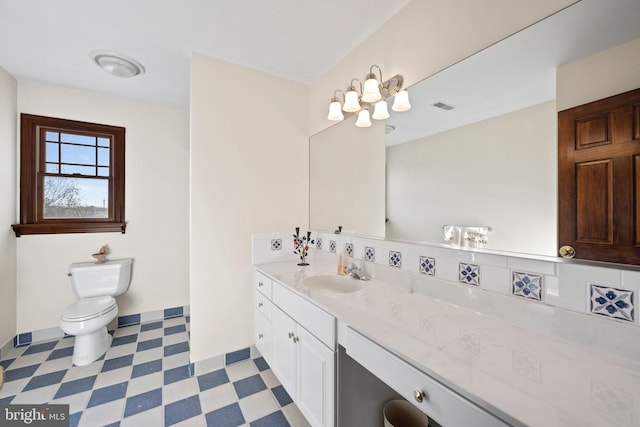 bathroom with toilet, tasteful backsplash, vanity, and tile patterned flooring