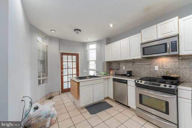 kitchen with white cabinetry, stainless steel appliances, backsplash, and kitchen peninsula