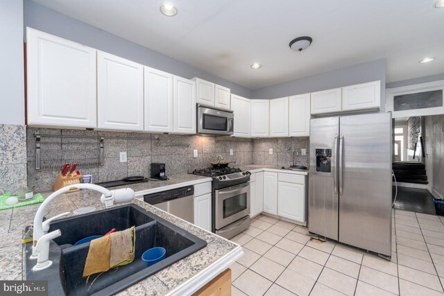 kitchen featuring light tile patterned flooring, white cabinetry, tasteful backsplash, stainless steel appliances, and sink