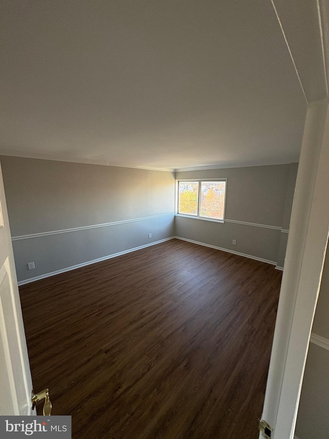 spare room featuring dark hardwood / wood-style floors and lofted ceiling