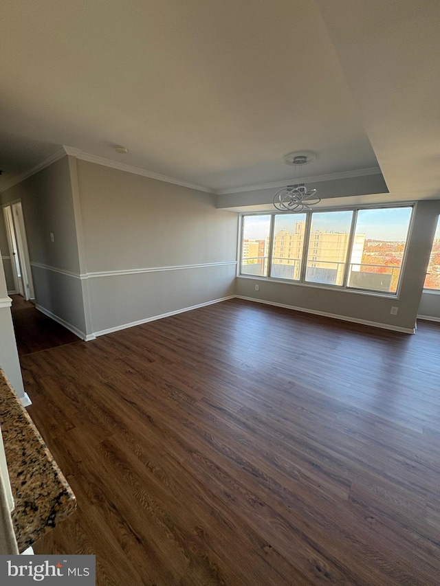 unfurnished living room with crown molding, dark wood-type flooring, and an inviting chandelier