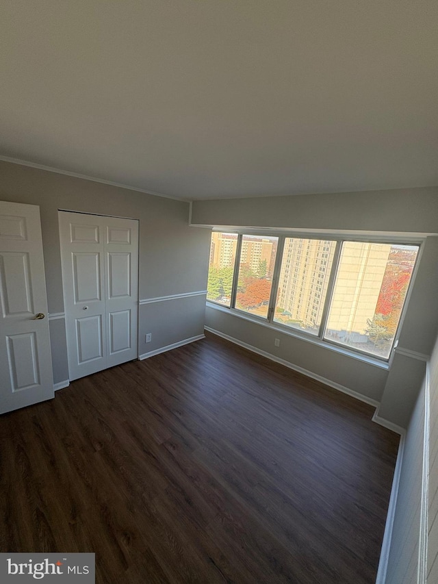 unfurnished bedroom with dark hardwood / wood-style flooring and a closet