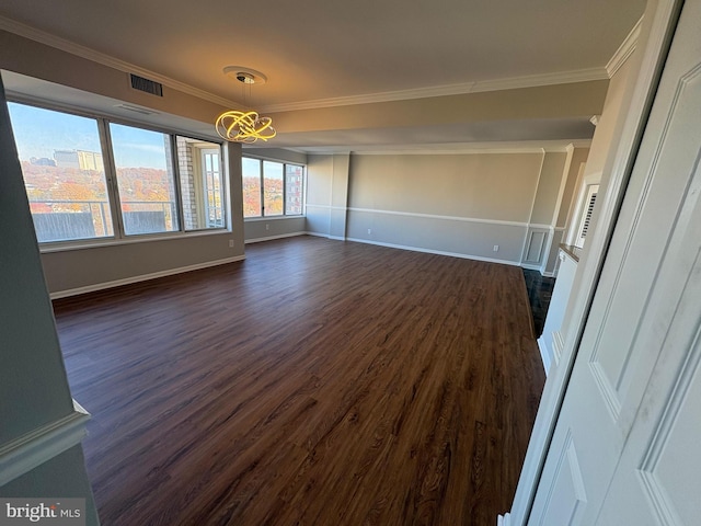 empty room with dark hardwood / wood-style flooring, an inviting chandelier, and ornamental molding