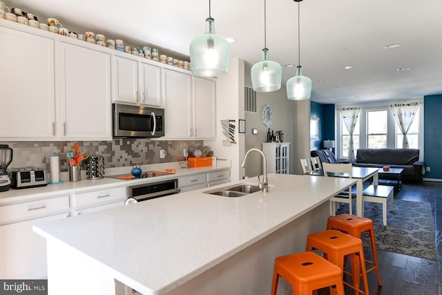 kitchen featuring appliances with stainless steel finishes, sink, a center island with sink, and dark hardwood / wood-style flooring