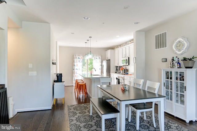 dining space featuring sink and dark wood-type flooring