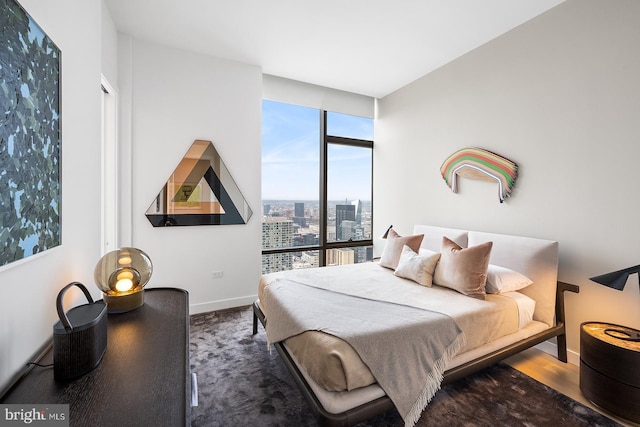 bedroom with a view of city, baseboards, and wood finished floors