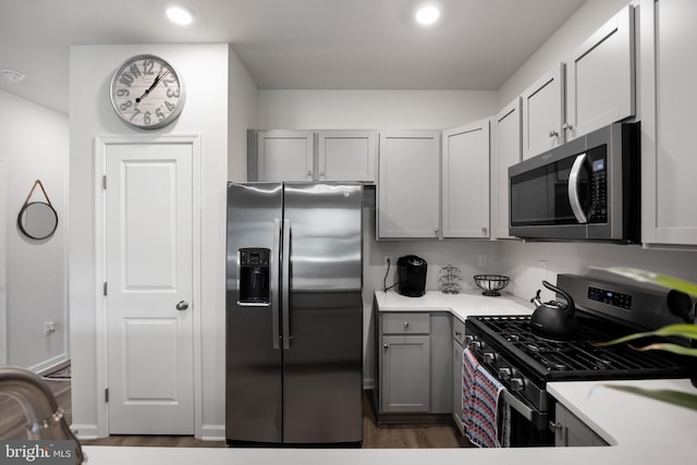 kitchen featuring gray cabinets, stainless steel appliances, and dark wood-type flooring