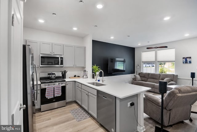 kitchen featuring light hardwood / wood-style flooring, kitchen peninsula, gray cabinets, stainless steel appliances, and sink