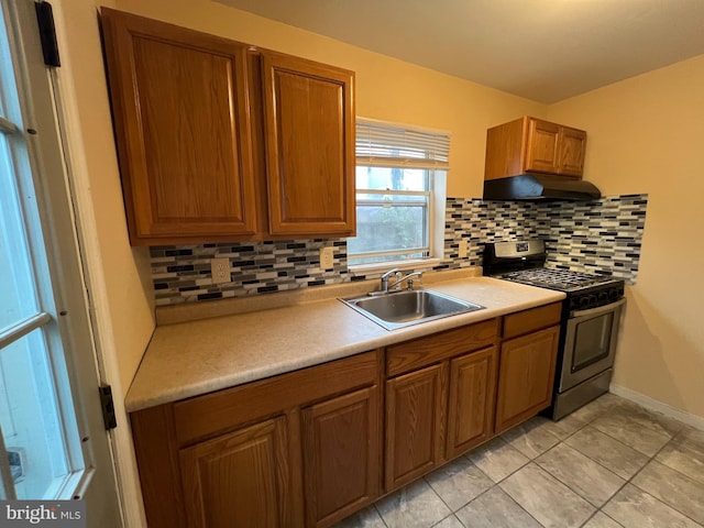 kitchen with sink, backsplash, stainless steel gas range oven, and light tile patterned flooring