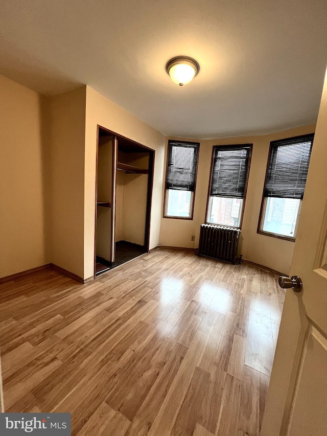 unfurnished bedroom featuring radiator, light hardwood / wood-style flooring, and a closet