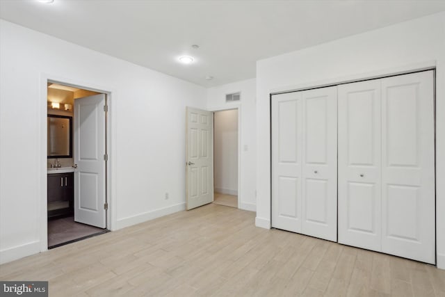 unfurnished bedroom with connected bathroom, light hardwood / wood-style floors, and a closet