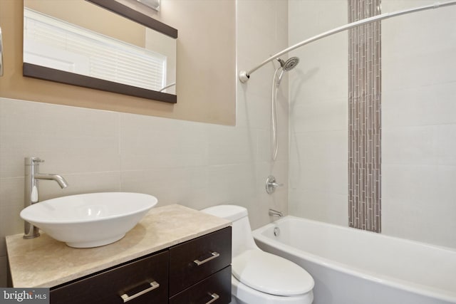 full bathroom featuring tiled shower / bath combo, vanity, tile walls, and toilet