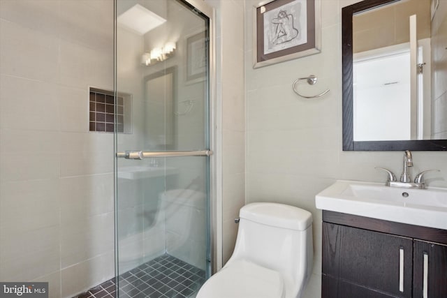 bathroom featuring vanity, a shower with shower door, tile walls, and toilet