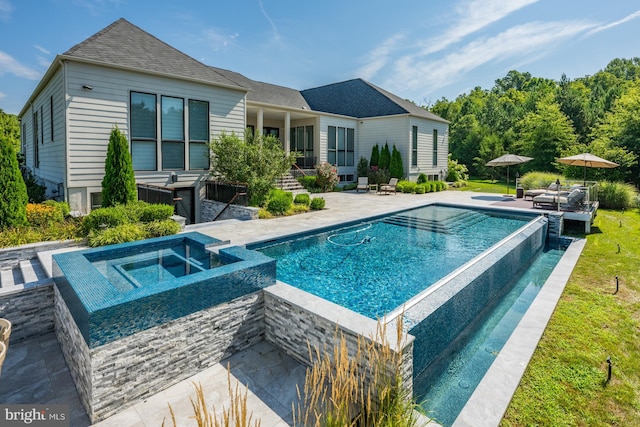 rear view of house featuring a swimming pool with hot tub and a patio