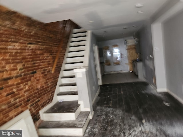 stairway featuring wood-type flooring and brick wall