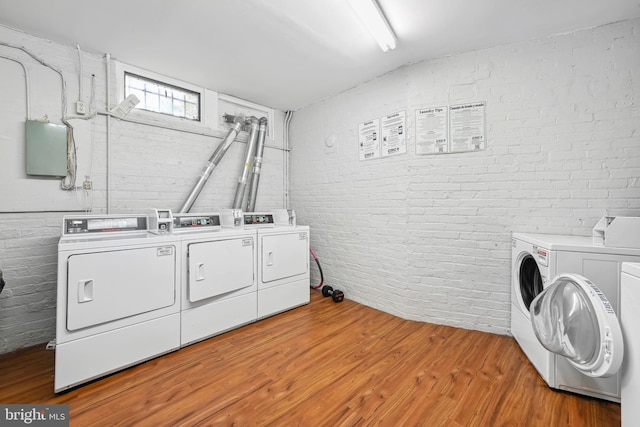 washroom featuring hardwood / wood-style floors, brick wall, and separate washer and dryer