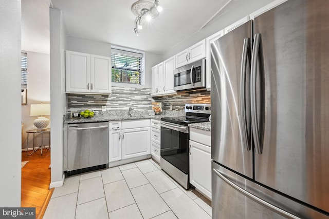 kitchen with white cabinetry, light hardwood / wood-style flooring, stainless steel appliances, light stone counters, and sink