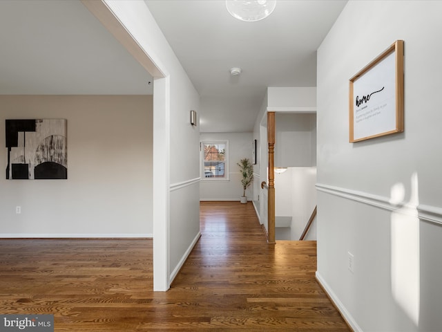 hall featuring wood finished floors, an upstairs landing, and baseboards