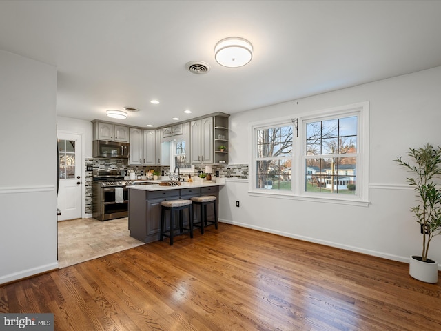 kitchen with decorative backsplash, a peninsula, stainless steel appliances, and open shelves