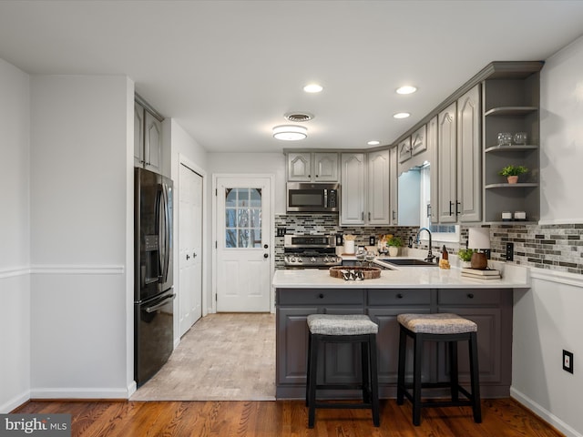 kitchen featuring gray cabinetry, a sink, stainless steel microwave, range, and black refrigerator with ice dispenser