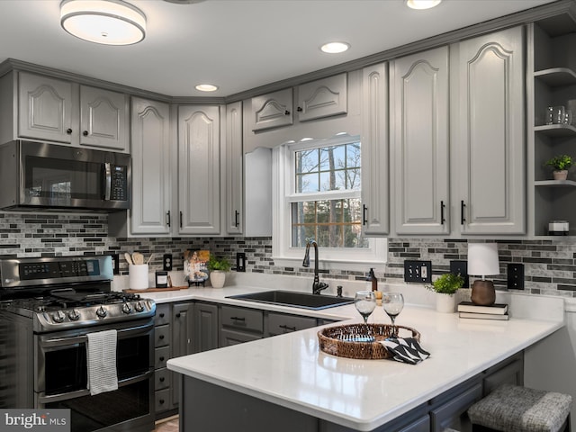 kitchen featuring a sink, gray cabinets, appliances with stainless steel finishes, a peninsula, and open shelves