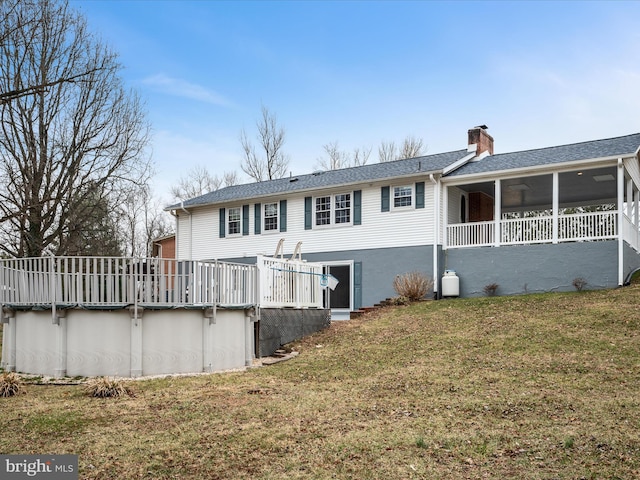 back of property featuring an outdoor pool, a yard, a chimney, and a sunroom