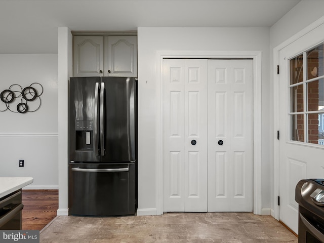 kitchen featuring baseboards, stainless steel range oven, dishwashing machine, light wood-style flooring, and black fridge with ice dispenser