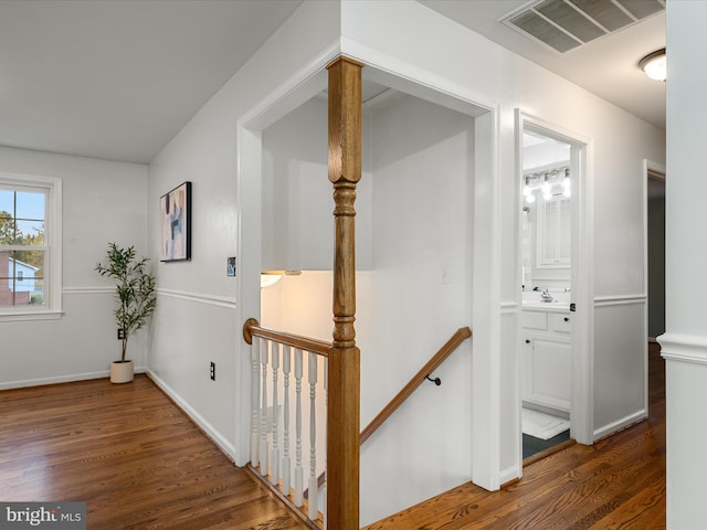 corridor featuring wood finished floors, an upstairs landing, visible vents, and a sink