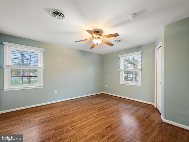 unfurnished bedroom with wood finished floors, visible vents, a closet, and baseboards