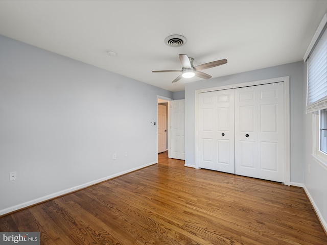 unfurnished bedroom with visible vents, a ceiling fan, wood finished floors, a closet, and baseboards