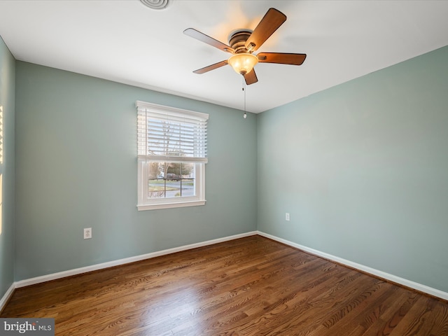 spare room featuring a ceiling fan, wood finished floors, and baseboards