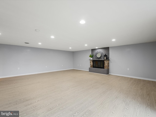 unfurnished living room with recessed lighting, a fireplace, baseboards, and light wood-style floors