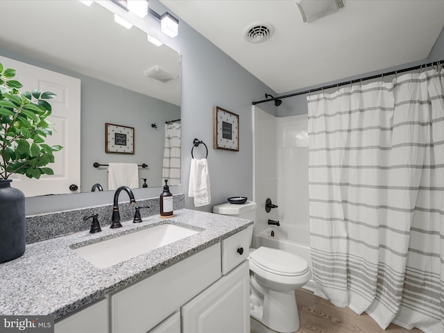 bathroom featuring visible vents, toilet, wood finished floors, shower / bath combination with curtain, and vanity