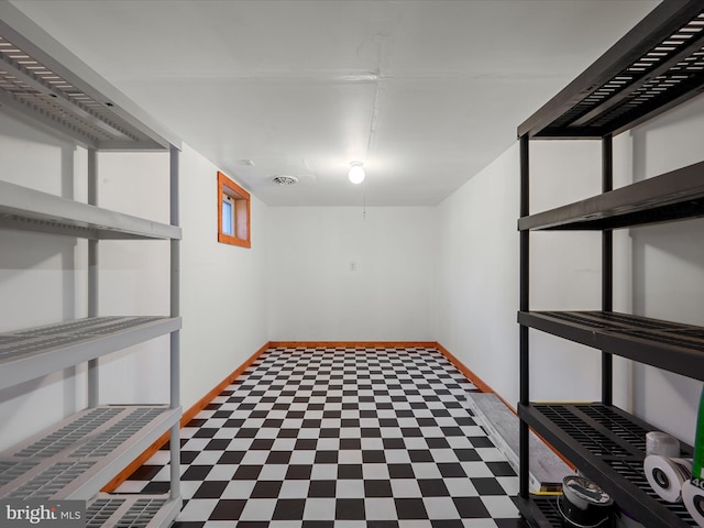 finished below grade area with tile patterned floors, visible vents, and baseboards