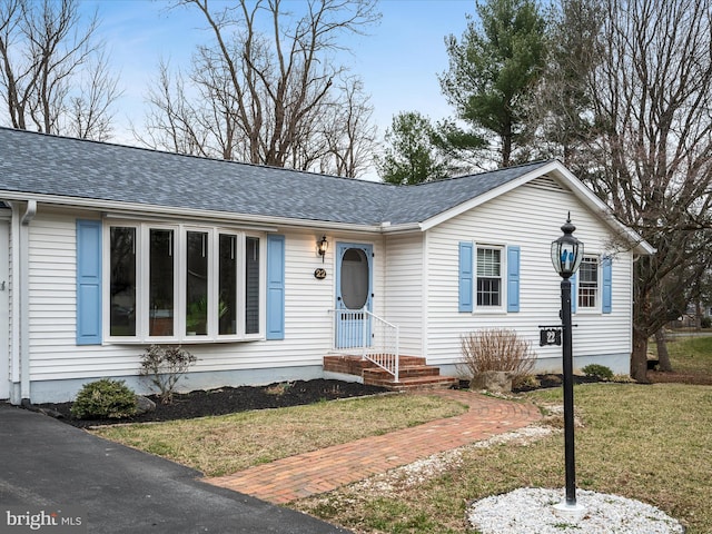 ranch-style house featuring roof with shingles and a front yard