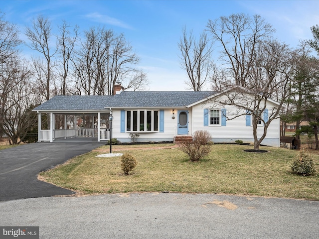 ranch-style home featuring an attached carport, driveway, a shingled roof, a chimney, and a front lawn