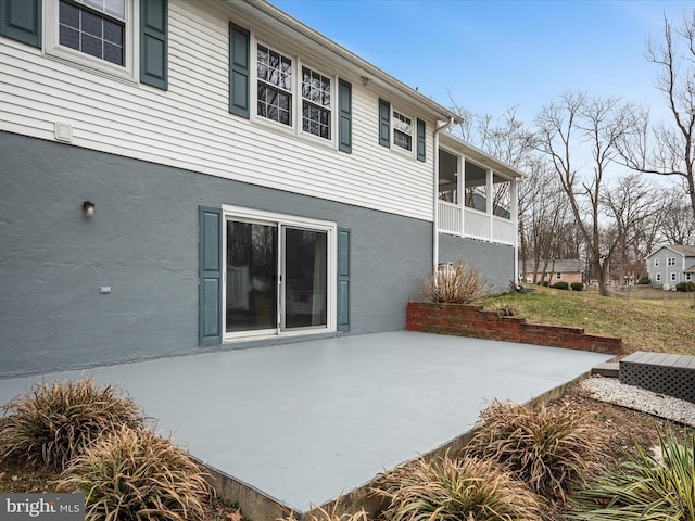 rear view of house with a patio area, a sunroom, and stucco siding