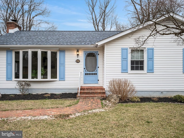 view of front of property featuring a chimney, entry steps, a shingled roof, and a front yard