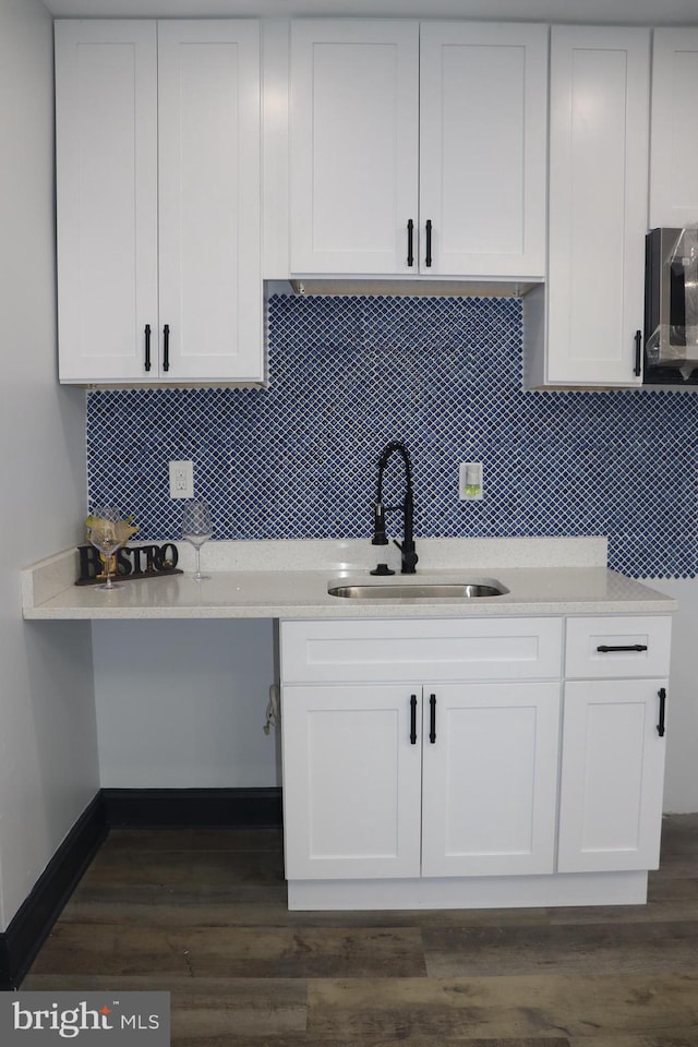 kitchen with tasteful backsplash, sink, white cabinets, and dark hardwood / wood-style floors