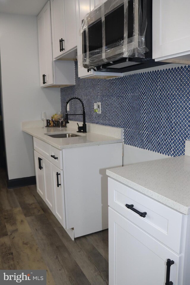 kitchen with decorative backsplash, sink, white cabinets, and dark hardwood / wood-style floors