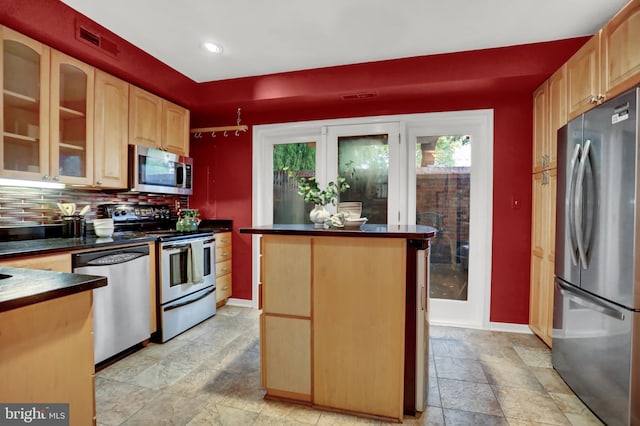 kitchen with backsplash, a kitchen island, light brown cabinets, and appliances with stainless steel finishes