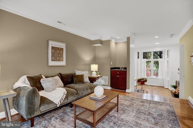 living room featuring ornamental molding, sink, and light hardwood / wood-style flooring