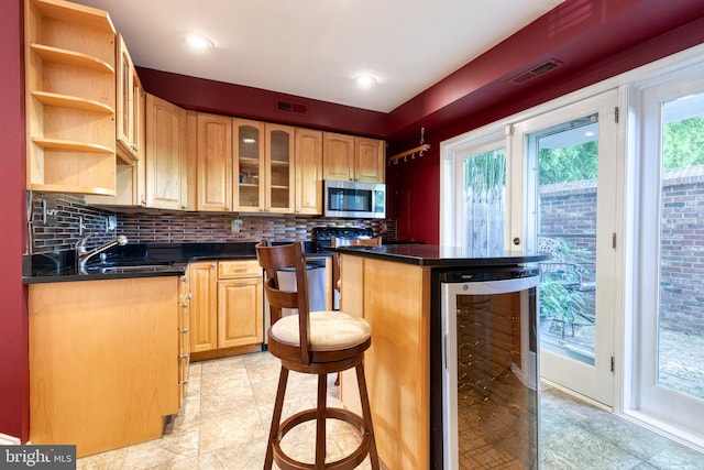 kitchen featuring decorative backsplash, a kitchen bar, beverage cooler, and sink